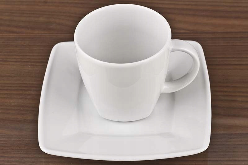 Biała filiżanka porcelanowa Lubiana Victoria pełna gorącej kawy na nowoczesnym stole