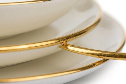 Zbliżenie na elegancki złoty pasek na krawędzi białego talerza z kolekcji Base Gold